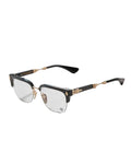 A pair of semi-rimless eyeglasses with a glossy black acetate frame, gold metal hinges, and clear lenses, displayed on a light gray textured surface.