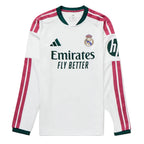 A white long-sleeve Real Madrid soccer jersey by Adidas, featuring dark green trim on the collar and cuffs, pink and white stripes on the sleeves, the Adidas logo on the right chest, the Real Madrid crest on the left chest, and the Emirates Fly Better sponsor logo across the center.