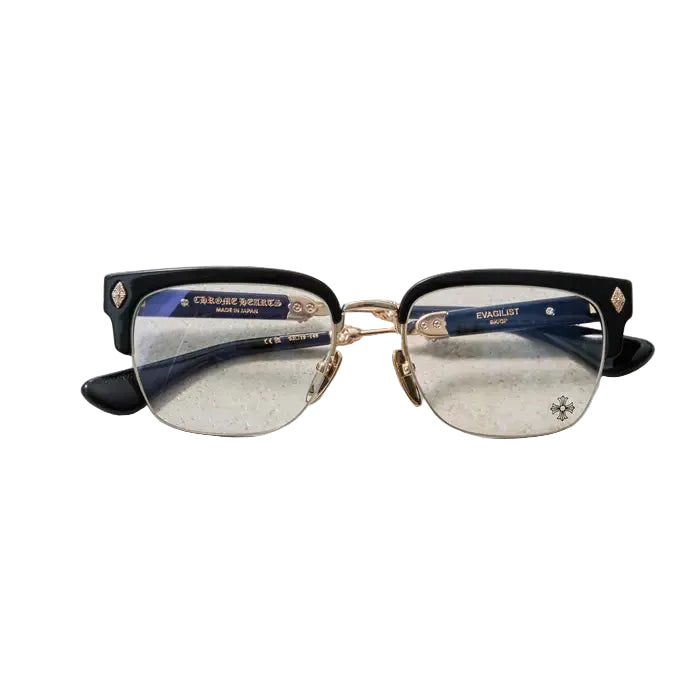 A pair of rimless eyeglasses with a black acetate front and gold metal bridge and hinge details, resting on a textured light gray surface.