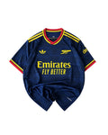 A navy blue Arsenal football jersey with yellow and red accents, featuring the Adidas logo, Arsenal cannon crest, and Emirates Fly Better sponsor text, laid flat on a white background.