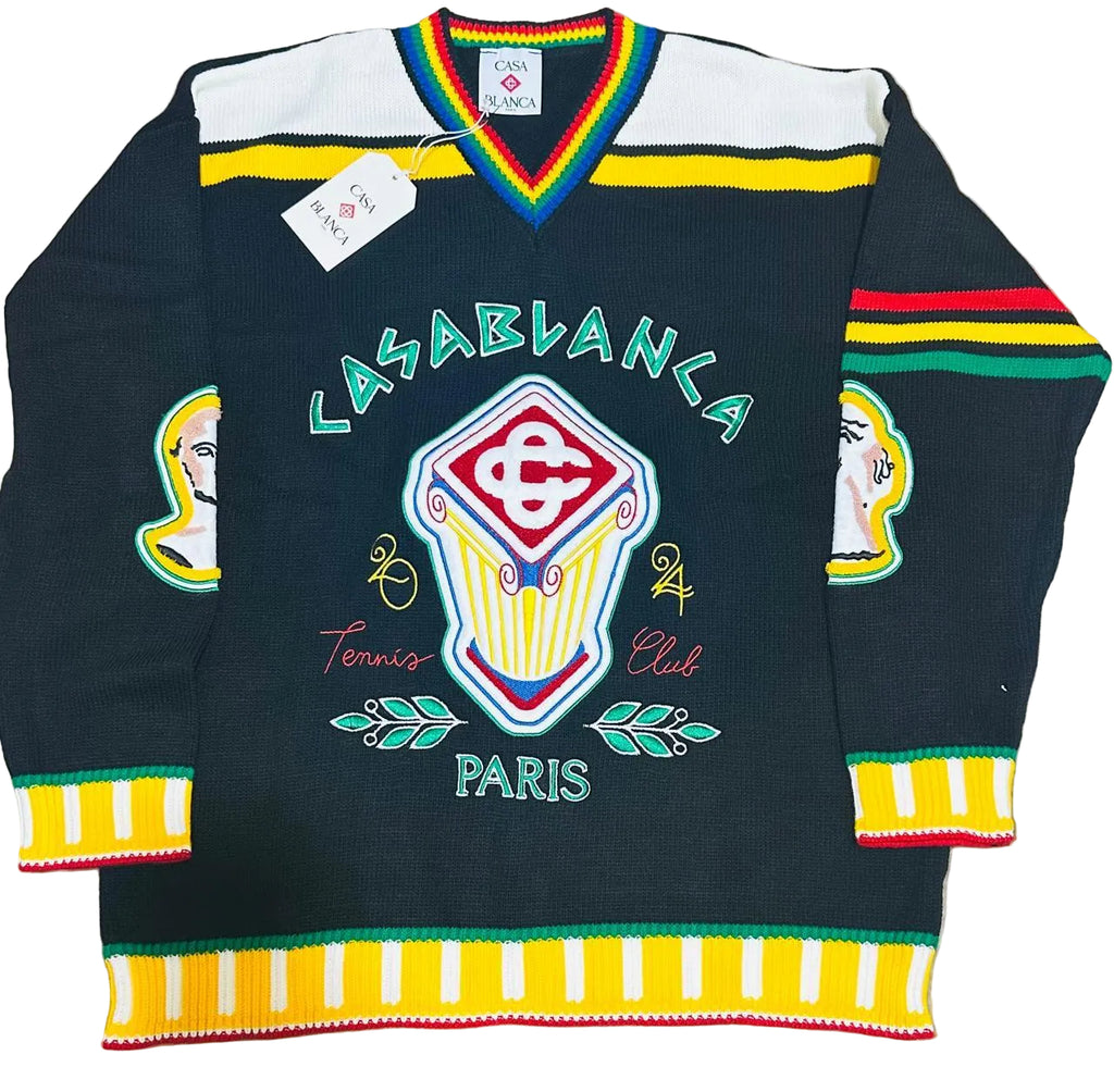 A vintage knit hockey-style sweater with 'LASABLANCA Tennis Club PARIS' text and a large central crest, laid flat on a beige faux-fur surface. The sweater is black with white shoulder panels, multicolor striped trim, and colorful graphic details.