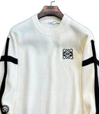 An off-white knit sweater with black stripe details on the sleeves and a black Loewe logo on the chest, hanging on a wooden hanger against a dark textured background.