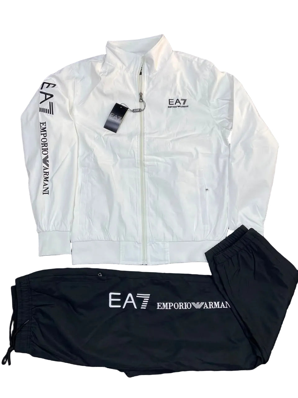 White zip-up jacket and black sweatpants set from Emporio Armani, featuring EA7 logos, laid flat on a gray textured background.