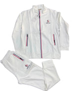 A white Moncler tracksuit set consisting of a zip-up jacket and matching sweatpants, laid flat on a dark gray textured background. The Moncler logo is embroidered on the left chest, and the iconic red, white, and blue stripe detail runs down the center zipper and the side pockets.
