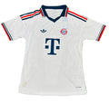 A white Adidas Bayern Munich soccer jersey with navy and red accents, featuring the Bayern Munich club crest and the T-Mobile logo, laid flat on a green grass background.