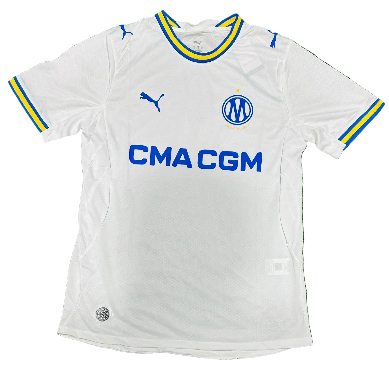 A white Inter Milan soccer jersey by Puma with blue and yellow trim, laid flat on a green grass-like surface. The jersey features the Inter Milan club crest and the sponsor logo CMA CGM.