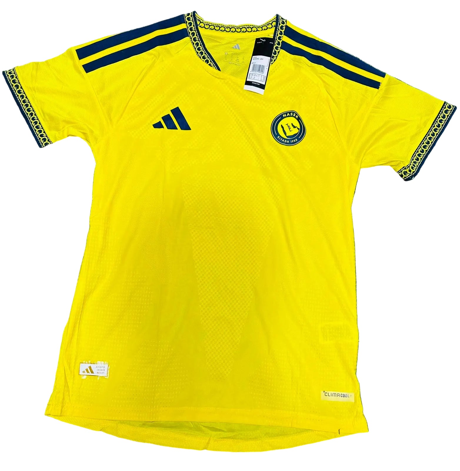 A yellow Adidas Golden State Warriors soccer jersey laid flat on green artificial turf. The jersey features navy blue shoulder stripes, a navy blue Adidas logo on the right chest, and the Golden State Warriors crest on the left chest.