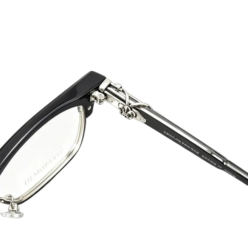 Close-up of a pair of eyeglasses with a glossy black frame and silver metal hinge details, shown on a clean white background.