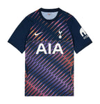 A navy blue short-sleeve soccer jersey with a colorful abstract diagonal line pattern in purple, pink, and orange across the body. It features the white Nike swoosh, the Tottenham crest, and the large white AIA sponsor logo on the front.